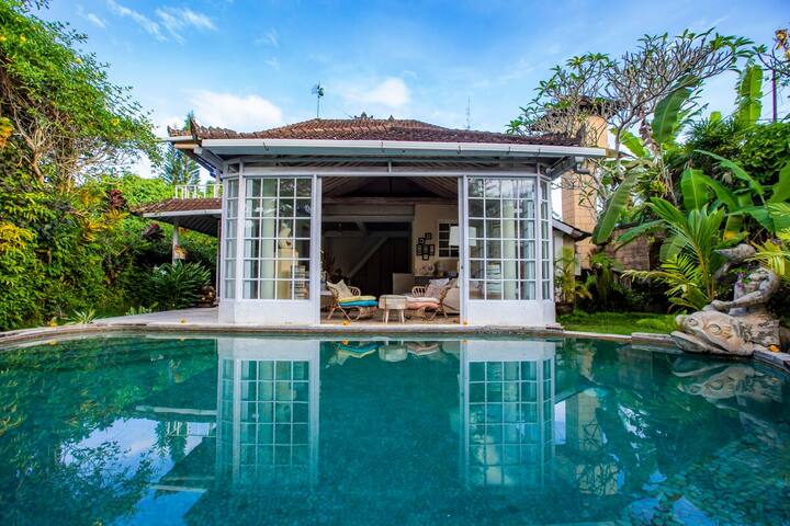 The pool running the length of the house under a blue sky